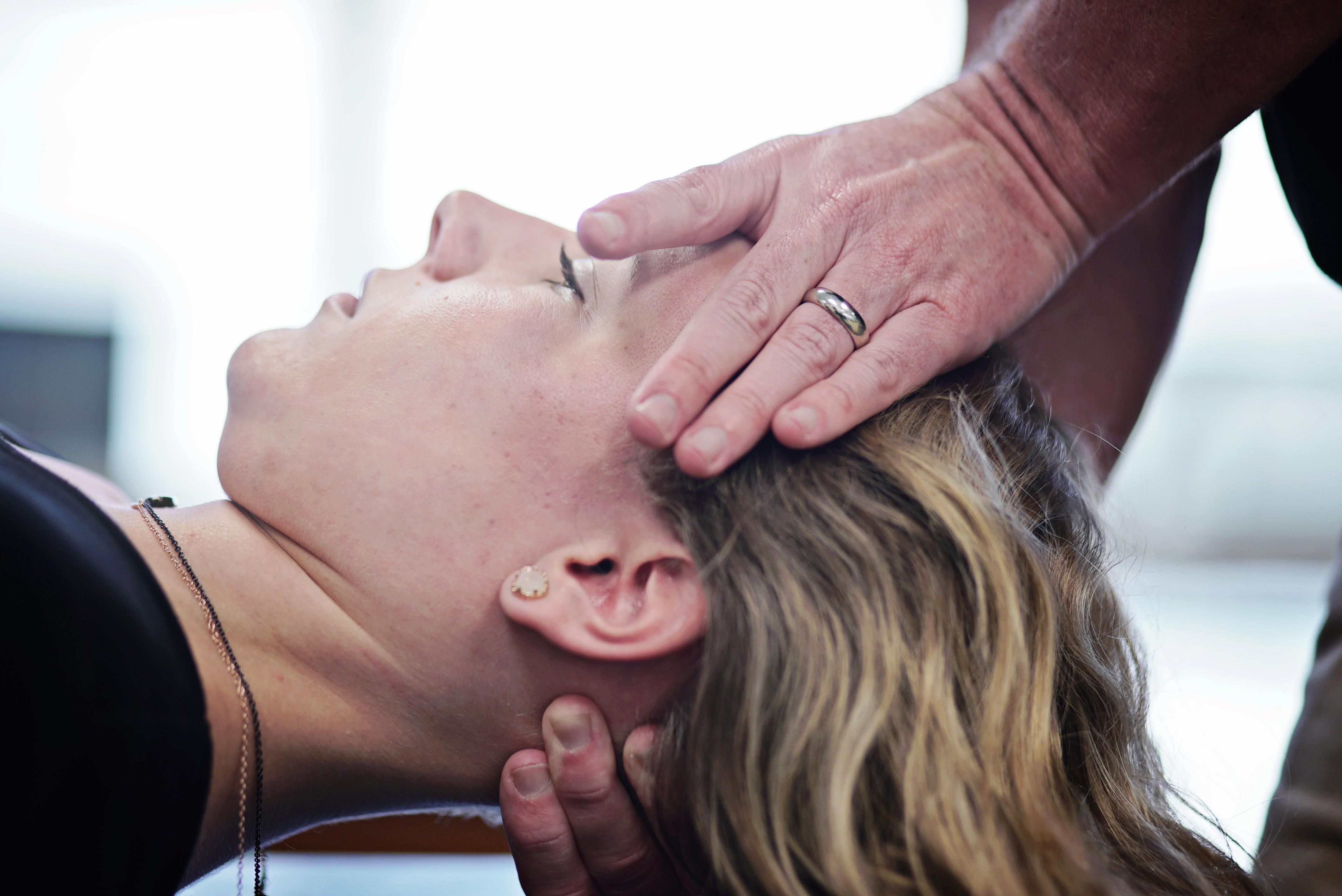 A female physical therapy patient with her neck and head held by a therapist